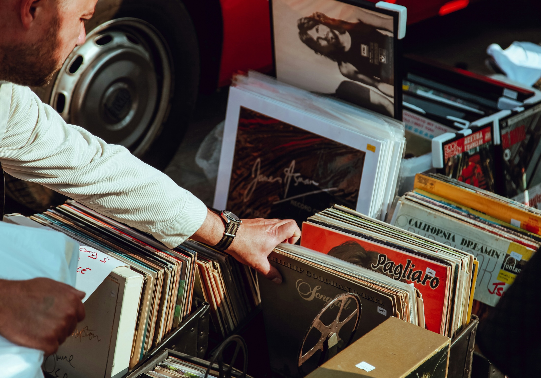A man looks through a stack of vinyl records for sale.