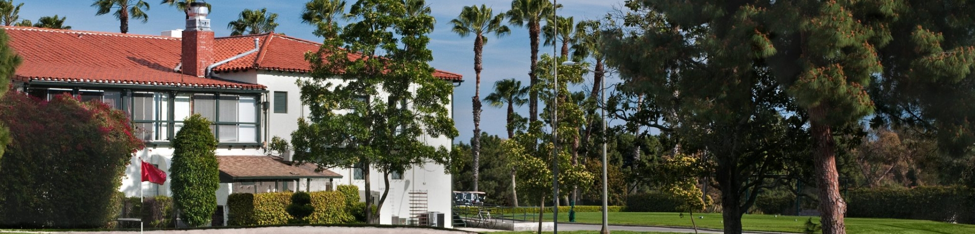 A green golf course with a building in the background. An American flag is flying.