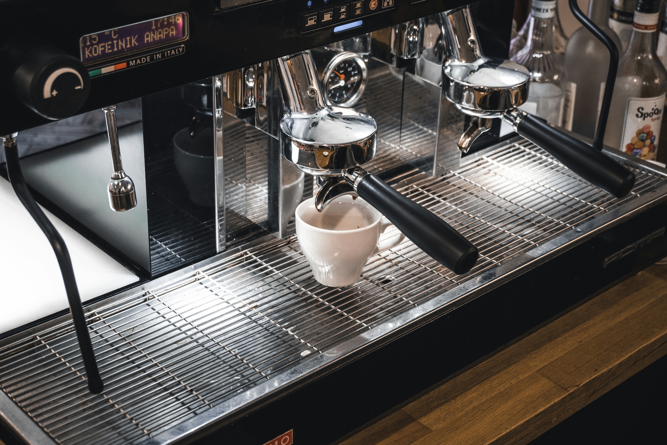 An espresso machine making a shot of espresso into a small white cup.